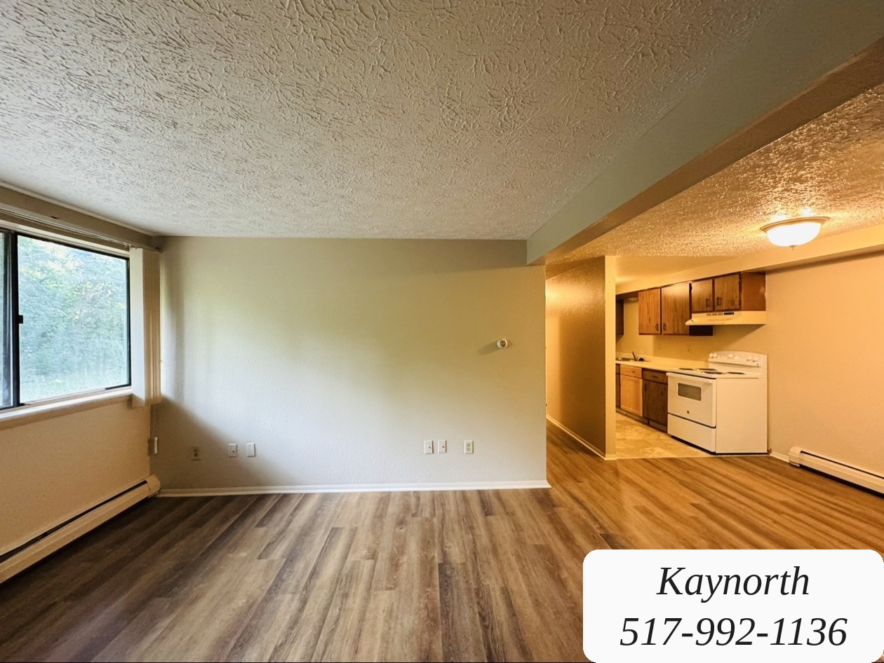 Living room of a Kaynorth apartment on Joshua Street in Lansing, with wood-look floors, opening into the kitchen