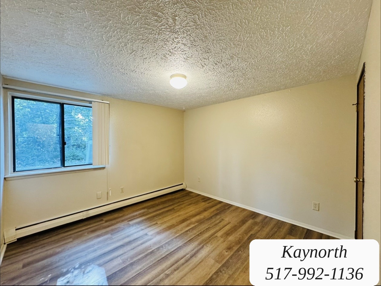 Bedroom with a large window and wood-look floors in a Kaynorth apartment