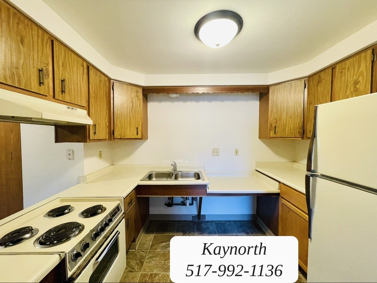 Kitchen with wood cabinets, range, and refrigerator in a Kaynorth apartment