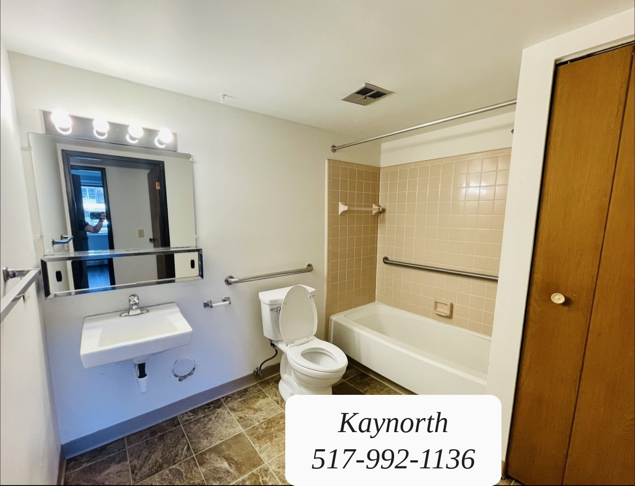 Bathroom with tub and shower, vanity mirror, and tile floor in a Kaynorth apartment