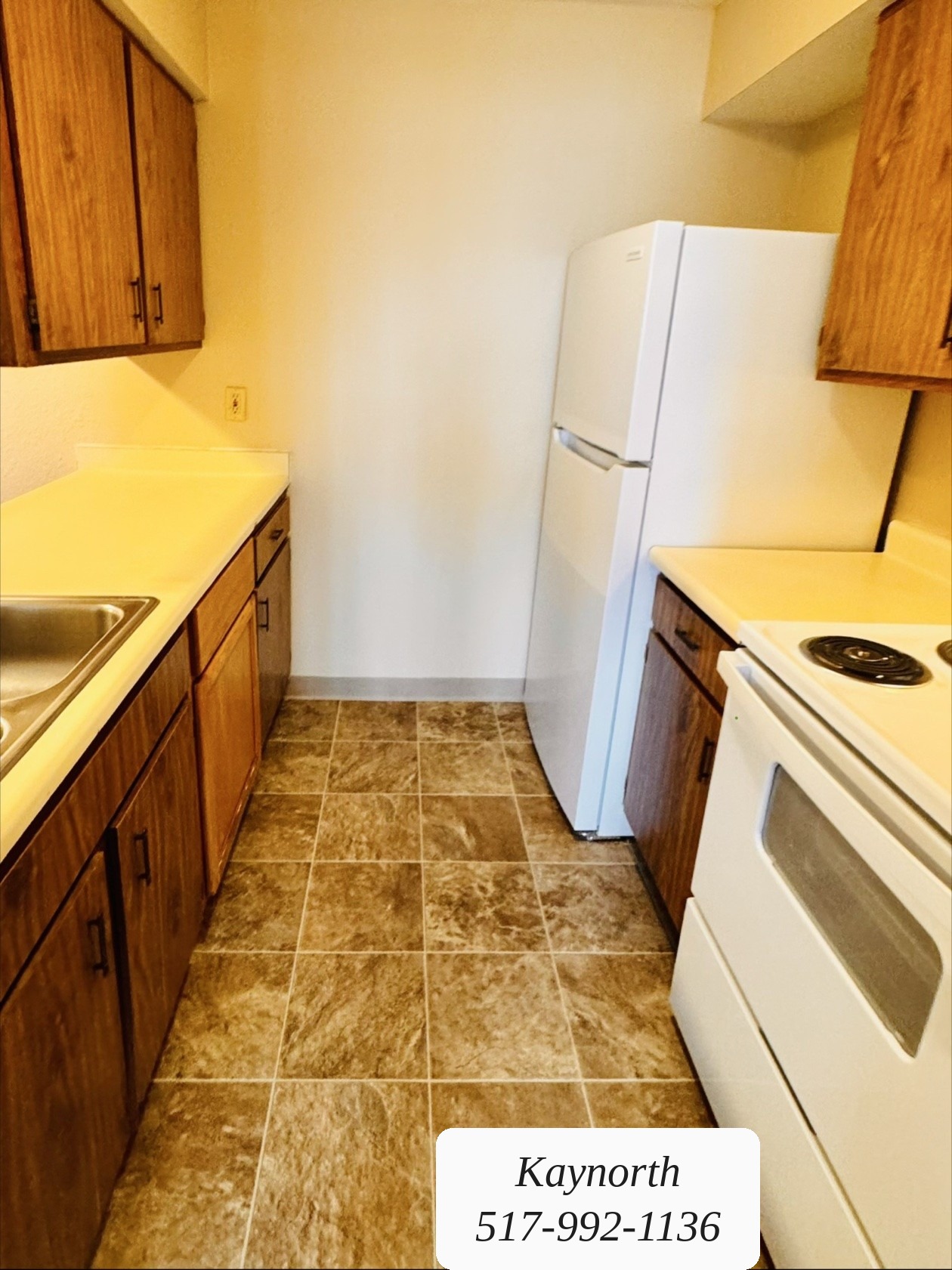 Kitchen with tile floor, range, and refrigerator in a Kaynorth apartment