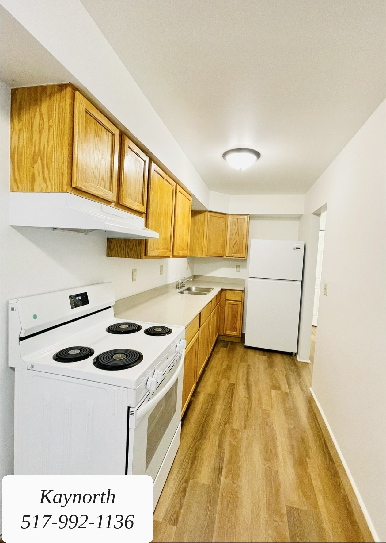 Kitchen with light wood cabinets and a white range in a Kaynorth apartment