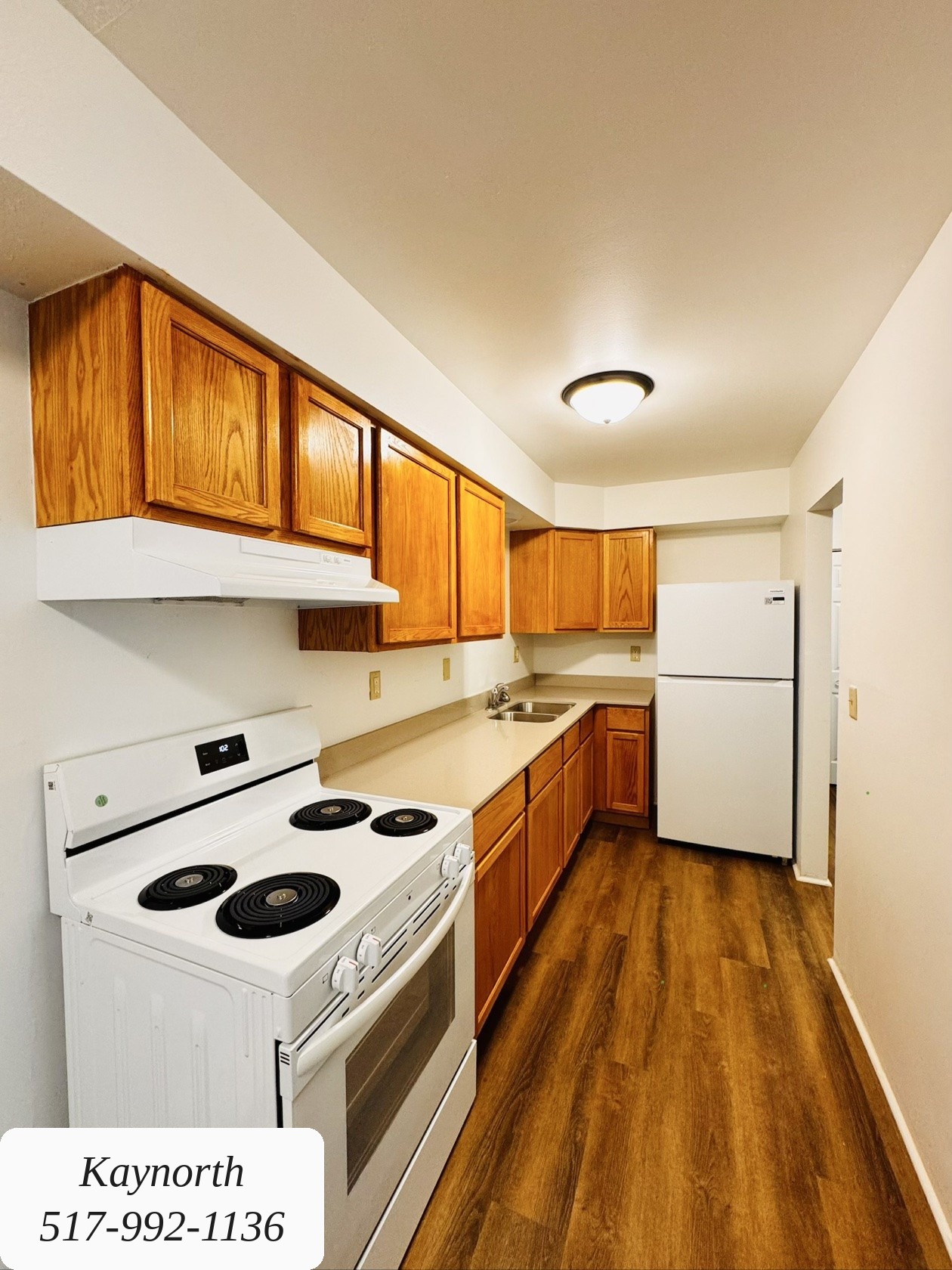 Kitchen with wood cabinets, range, and refrigerator in a Kaynorth apartment